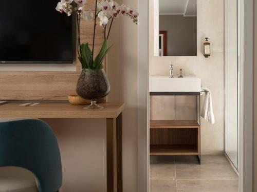 a bathroom with a sink and a vase with flowers on a table at Hotel Livata Mountain Wellness in Subiaco