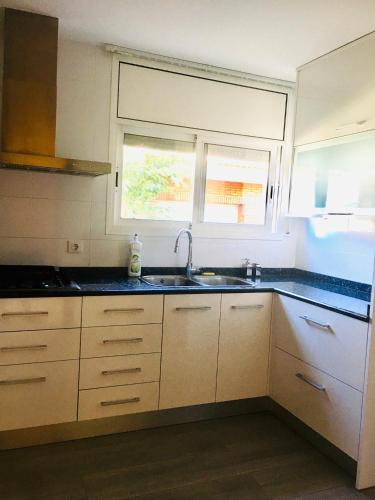 a kitchen with white cabinets and a sink and a window at Casa de Aurora in Rubí