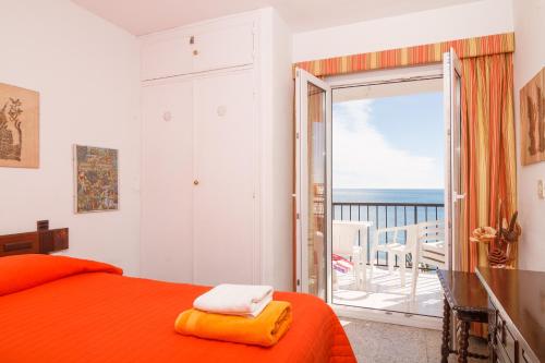 ネルハにあるBahia 57 Apartments Casasolのベッドルーム(オレンジ色のベッド1台、バルコニー付)