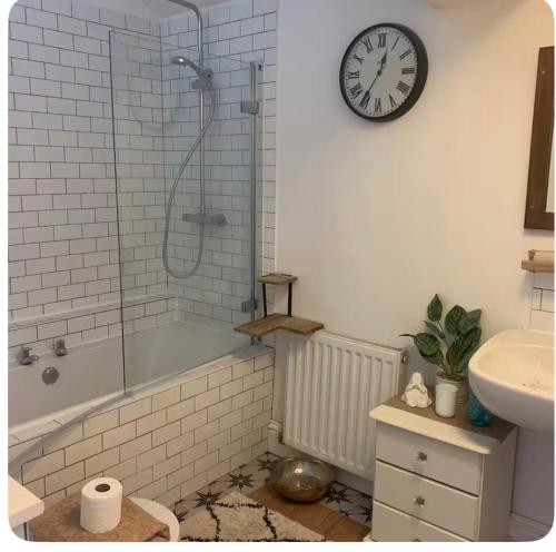 a bathroom with a shower and a clock on the wall at Honeydon in Eaton Socon