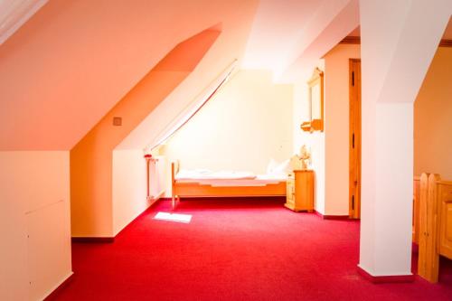 an attic room with a bed and a red carpet at Hotel Schloßblick Trebsen in Trebsen