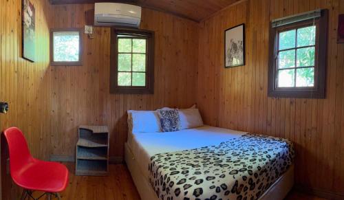 a bedroom with a bed and a red chair at Onda Azul Back Unit A & B in Ponta do Ouro