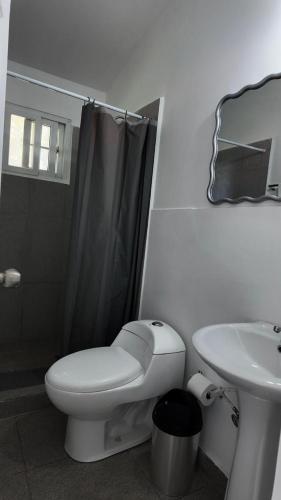 a white bathroom with a toilet and a sink at Hotel San Pedro de Taboga in Taboga