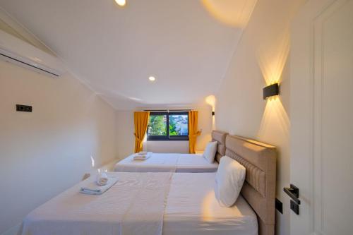 two beds in a white room with a window at Villa Prestige 2 in Fethiye