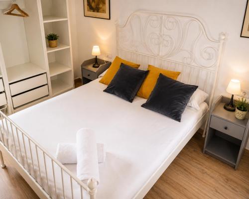 a bedroom with a large white bed with yellow pillows at Apartamentos Turísticos Teatro Romano by CartagenaSpain in Cartagena