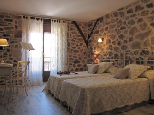 a bedroom with a bed and a stone wall at Casa del Tío Benito 2H in Molinos de Duero