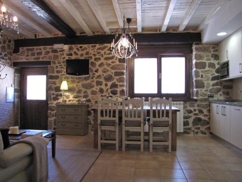 a living room with a table and a stone wall at Casa del Tío Benito 2H in Molinos de Duero