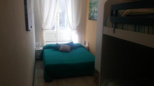 a small bedroom with a blue bed in front of a window at Casa Barnaba in Siracusa