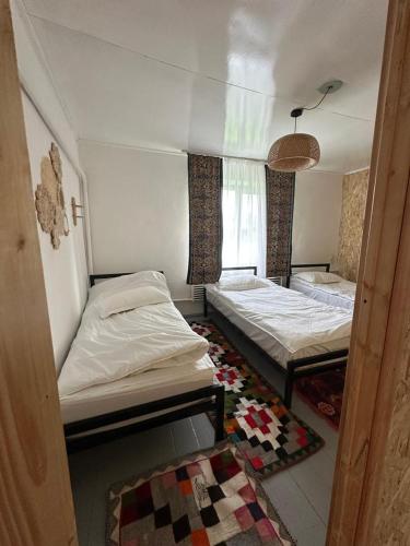 a room with two beds and a window at Gulazyk guest house in Bokonbayevo
