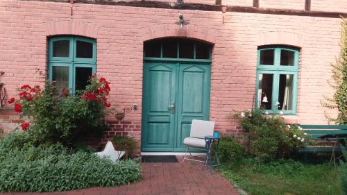 a brick building with a blue door and a white chair at Bülitz33 in Luckau