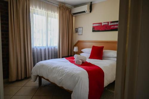 a hotel room with a bed with a red and white blanket at Flamingo Holiday Flats in St Lucia