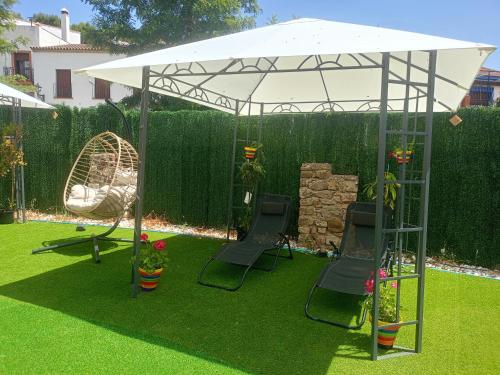 a white canopy in a garden with chairs and a swing at Villa Cultural MONTELUCÍA in Montecorto