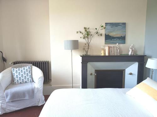 a bedroom with a bed and a chair and a fireplace at Clos Florésine B&B in Venette