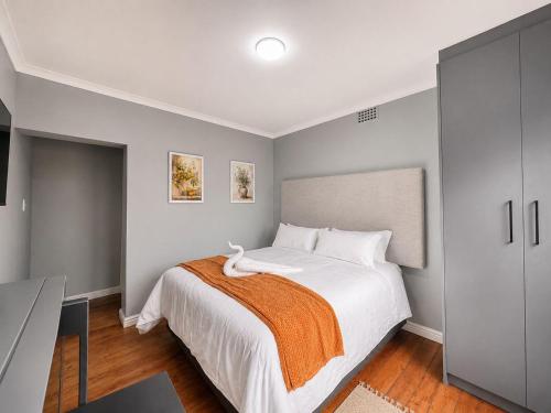 a bedroom with a large white bed with an orange blanket at Pecan Tree Lodge in Cape Town