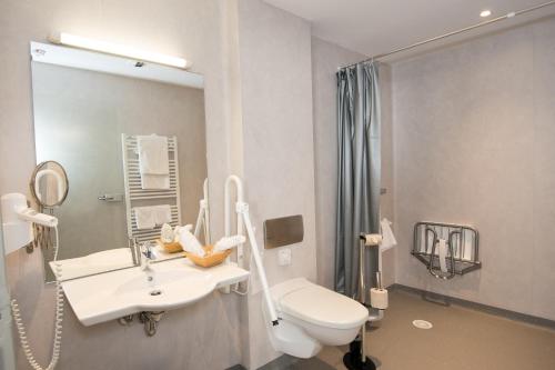 a bathroom with a white sink and a toilet at Logis Hôtel-Restaurant Auberge Du Mehrbachel in Saint-Amarin