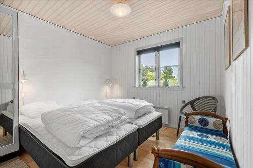 a bedroom with a bed and a window and a chair at BV225-Blavand-Blavandvej-5-E in Blåvand