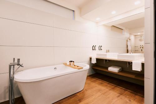 a white bathroom with a tub and two sinks at Hotel Aquafalls in Caniçada