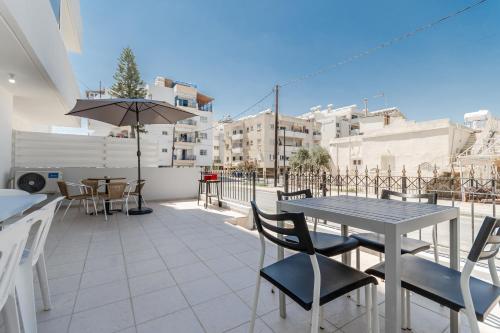 a patio with a table and chairs and an umbrella at Andreas Beachfront Hostel in Larnaca