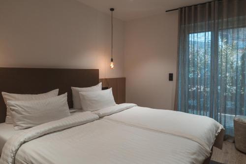 a bedroom with a large white bed with a window at Egerner Chalet in Rottach-Egern