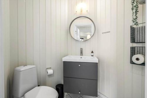 a white bathroom with a toilet and a mirror at 393-Harboore-Fourmivej-10 in Harboør