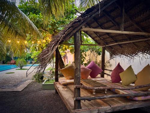a bed with colorful pillows in a straw hut at Papaya Hikkaduwa in Hikkaduwa