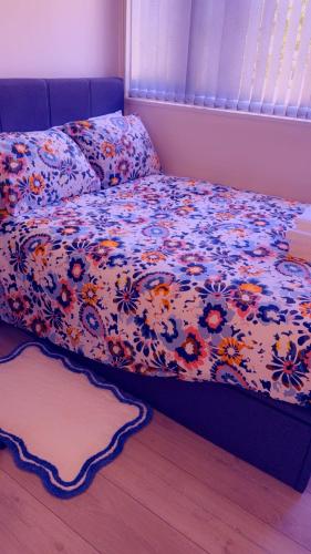 a bed with a floral comforter on it in a bedroom at 32 Hatton Guest House in Milton Keynes