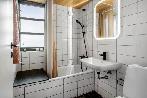 a white tiled bathroom with a sink and a tub at 531-Lemvig-Lokkevej-59-C in Lemvig