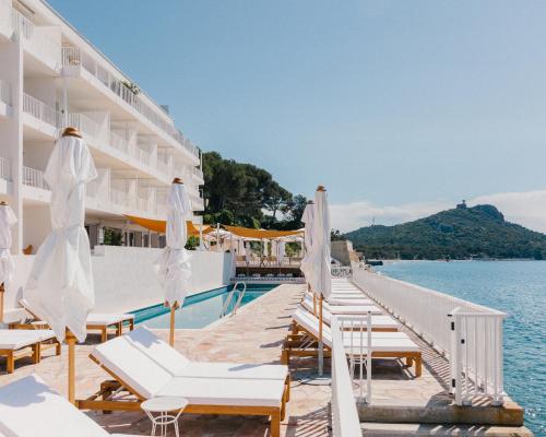 a pool with chairs and umbrellas next to the water at Les Roches Rouges, a Beaumier hotel in Saint-Raphaël
