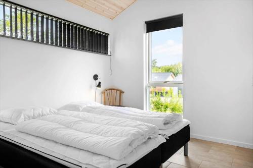 a white bedroom with a large bed with a window at LF14344-Roslev-Folvigvej-44 in Roslev