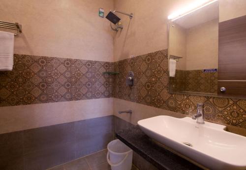 a bathroom with a sink and a mirror and a toilet at Manjhi Stay in Tiruchirappalli