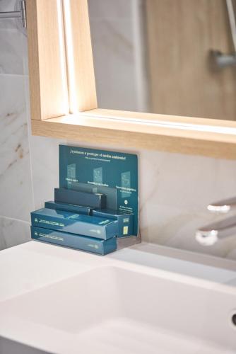 two boxes sitting on a shelf under a bathroom mirror at Silken Gran Hotel del Sella in Ribadesella