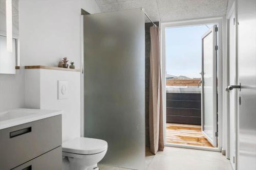 a bathroom with a toilet and a sliding glass door at 394-Harboore-Hermodsvej-8 in Harboør