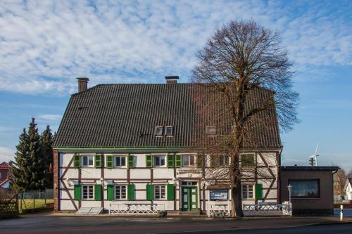 ein großes Haus mit grünen Türen und einem Baum in der Unterkunft Lindenschänke in Werl