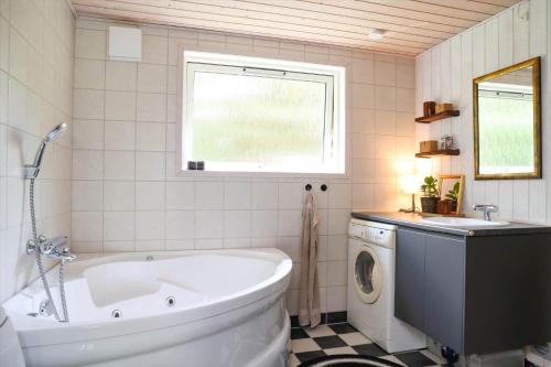 a bathroom with a tub and a washing machine at 10055-1-Rorvig-Lindevangen-4 in Rørvig