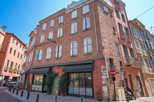 a brick building on a city street with a stop sign at Le cocoon de Pome et Leon in Perpignan