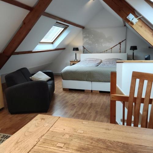 a attic bedroom with a bed and a chair at Logies op Dreef in Driebergen