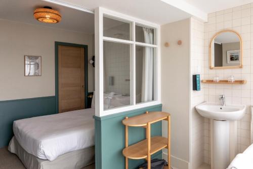 a room with a bed and a sink and a mirror at Hôtel Restaurant Bellevue in Bréhat
