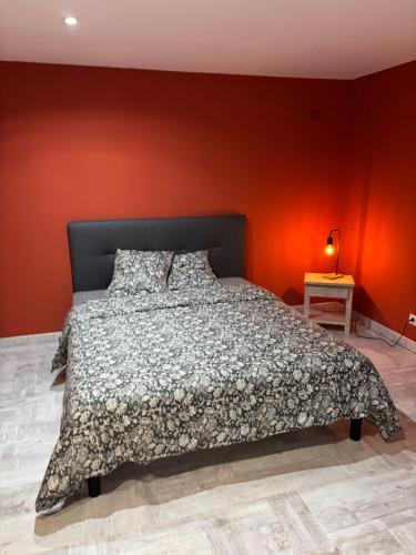a bedroom with a bed with an orange wall at L'Estel in Hasparren