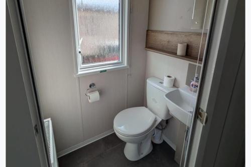 a small bathroom with a toilet and a sink at Seaside Haven Hunstanton 2026 Model in Hunstanton