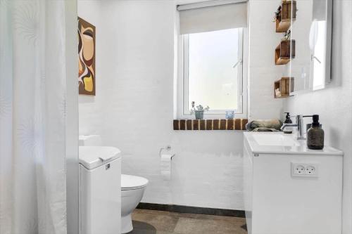 a white bathroom with a toilet and a window at LF10004-Thyholm-Agertoften-4 in Thyholm