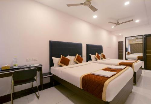 two beds in a room with a desk and a bedroom at Manjhi Stay in Tiruchirappalli
