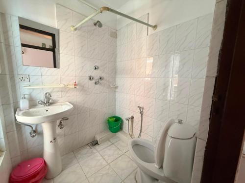 a white bathroom with a toilet and a sink at Lux Apartment in Kathmandu