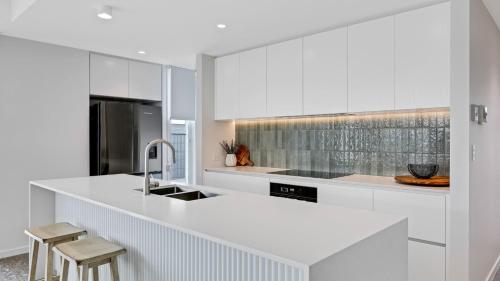 a white kitchen with a sink and a counter at Luxury Townhouse Maroochydore in Maroochydore