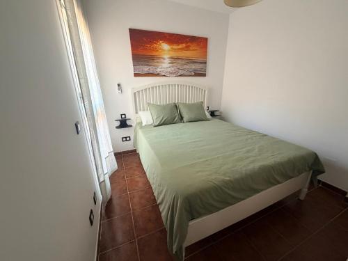 a bedroom with a bed with a green comforter at Brisa de la Barrosa in Novo Sancti Petri