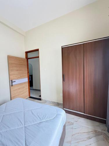 a bedroom with a bed and a wooden closet at Modern 1BR Apartment with Pool & Sauna Kampala in Kira