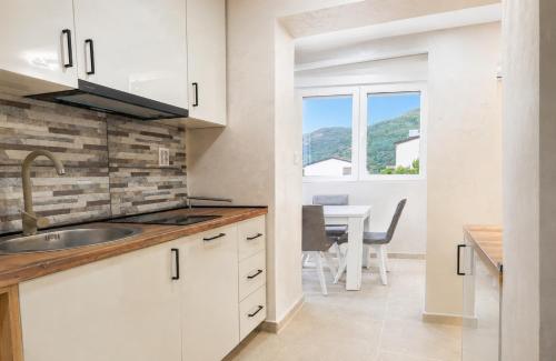 a kitchen with a sink and a dining room with a table at Dorado Apartments in Kavač
