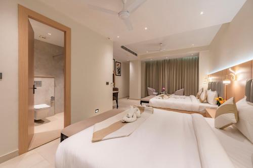 a large white bedroom with two beds and a bathroom at Hotel Meera Palace in Varanasi