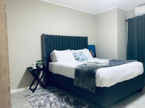 a bedroom with a large bed with a green headboard at The Penguin Nest in Gaborone