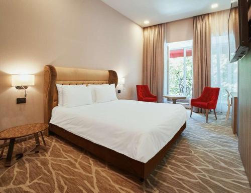 ein Schlafzimmer mit einem großen Bett und roten Stühlen in der Unterkunft Radisson Hotel City Centre Odesa in Odessa