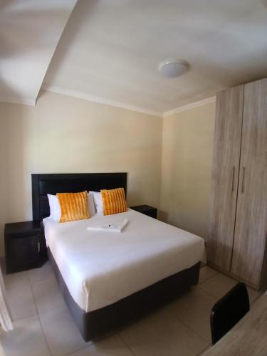 a bedroom with a large white bed with orange pillows at Jate Guest House in Maseru